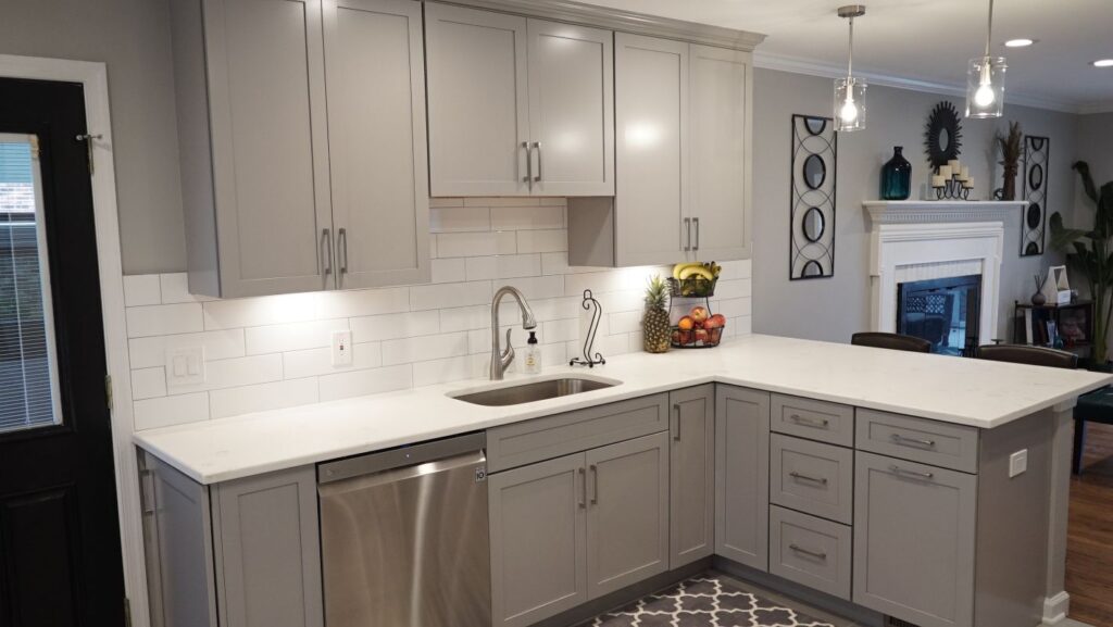 Kitchen with gray shaker cabinets, white quartz countertops, subway tile backsplash, and stainless steel dishwasher