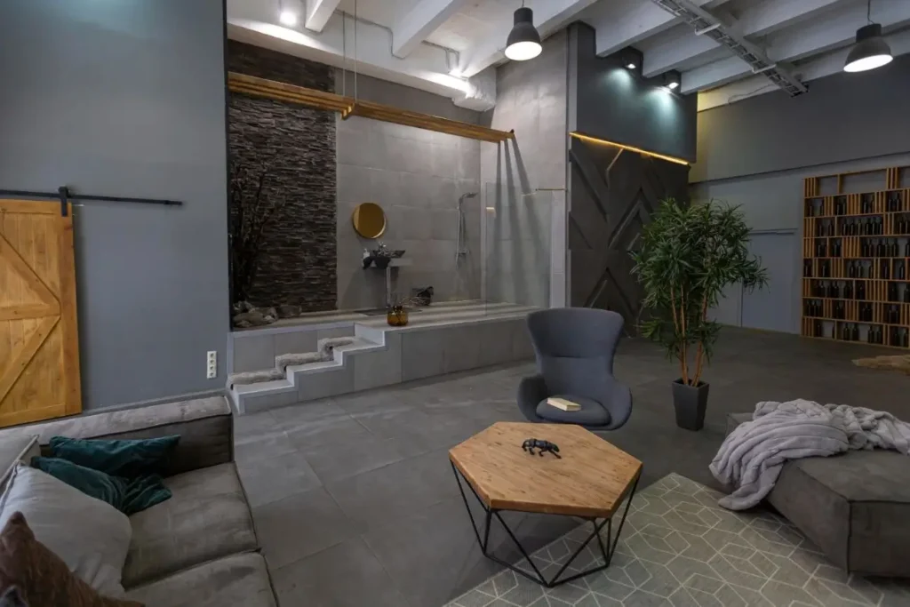 Modern finished basement with industrial design, seating area, and custom spa-style soaking tub with glass partition