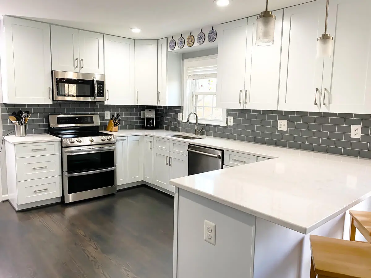 White shaker kitchen with gray subway tile backsplash and quartz countertops