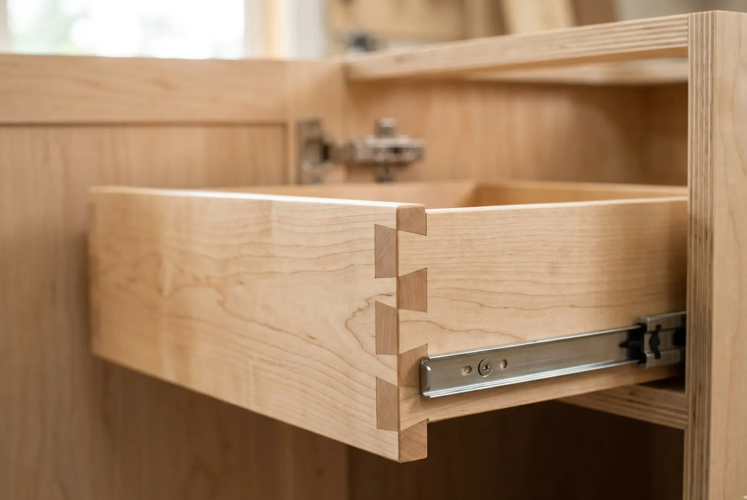 Hand-cut dovetail drawer joint in solid maple, mounted in a Baltic birch plywood kitchen cabinet box with a full-extension ball-bearing slide