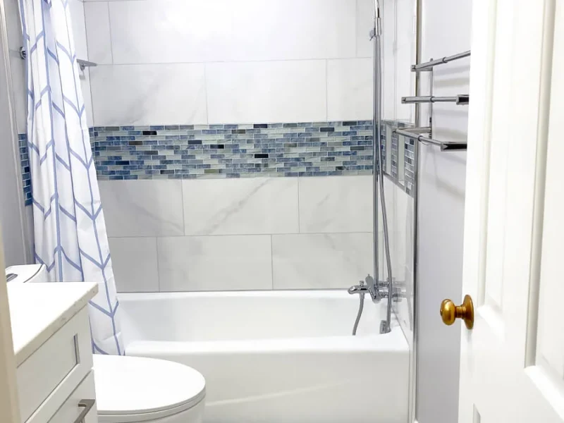 Bathtub shower combo with accent tile strip and modern bathroom remodel