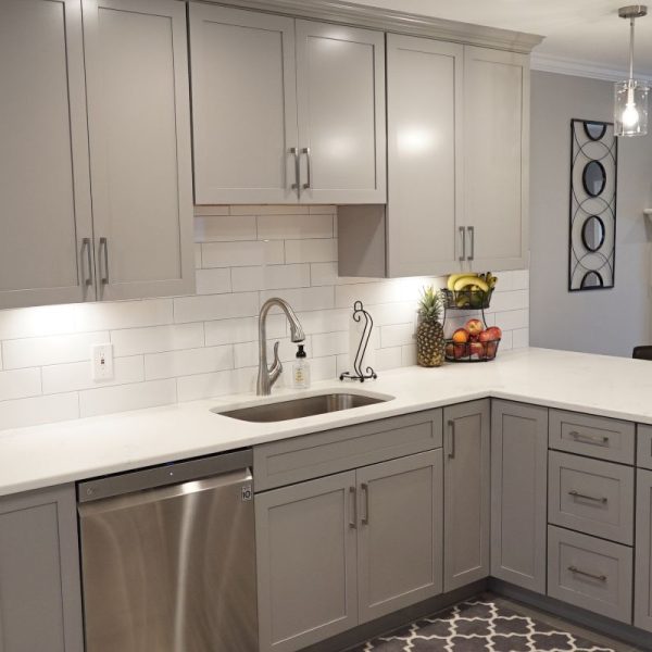 Kitchen with gray shaker cabinets, white quartz countertops, subway tile backsplash, and stainless steel dishwasher
