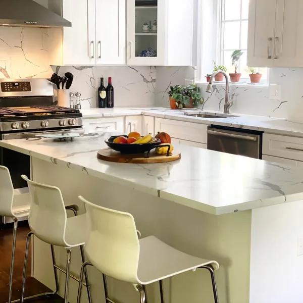Kitchen island with seating and quartz countertop overhang in modern white kitchen design