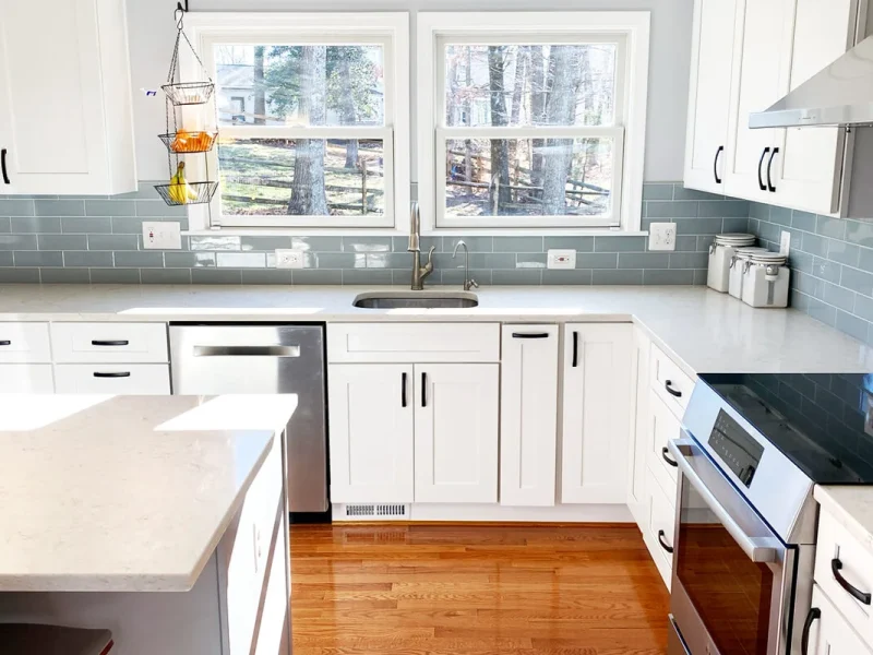Kitchen remodel showing sink under window and adjacent cooking area with quartz countertops